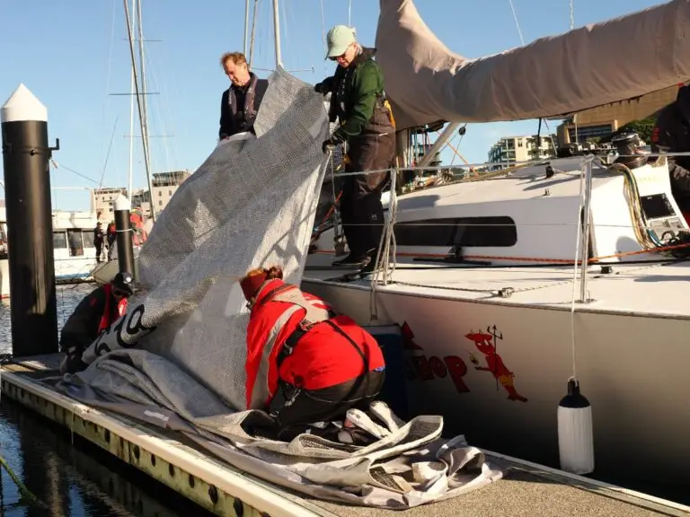 Crew flaking a sail on the dock after racing