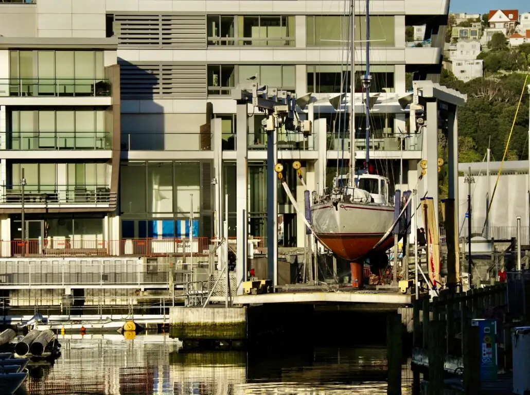 A yacht lifted in the slings of the Chaffers Marina boat lift, with Clyde Quay Wharf apartments behind