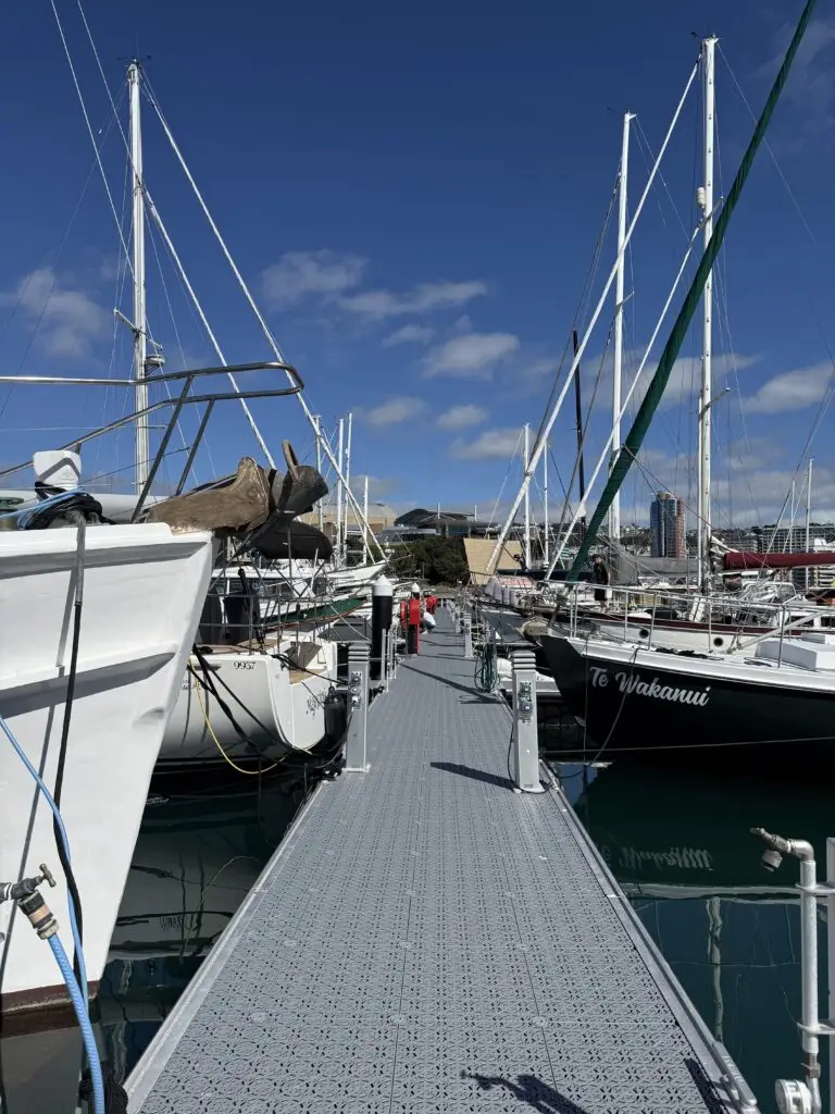 A pier at Chaffers Marina lined with moored yachts, with a person walking along it