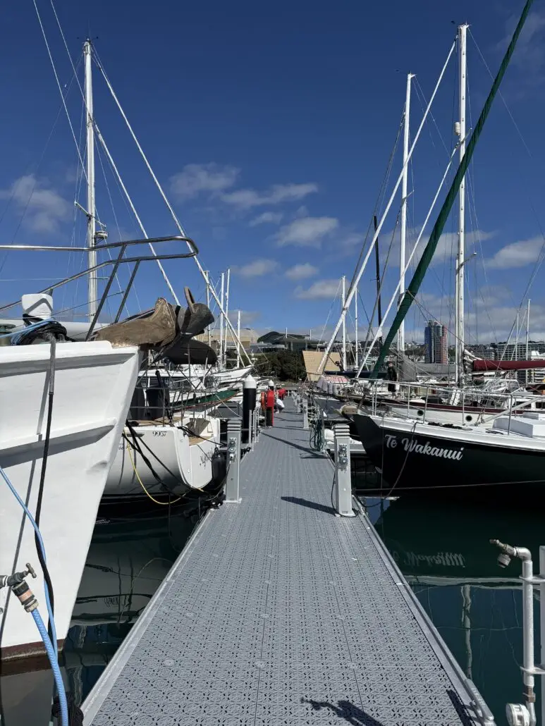 A pier at Chaffers Marina lined with moored yachts, with a person walking along it